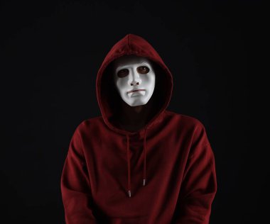 Anonimlik. Karanlık arka planda maskeli bir adam.