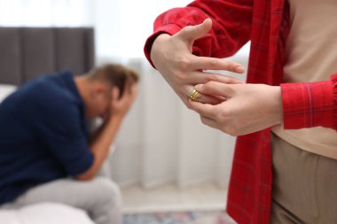 Kocasının içeride yaptığı ihanetten sonra nişan yüzüğünü çıkaran kadın, seçici bir odak noktası.