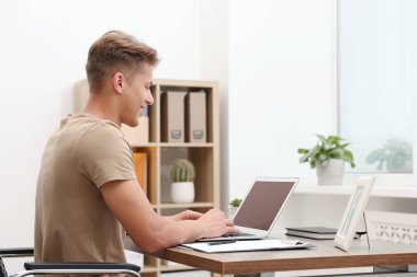 İçerideki ahşap masada dizüstü bilgisayar kullanan metin yazarı