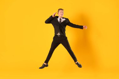 Turuncu arka planda akıllı telefondan konuşan işadamı zıplıyor