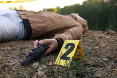 Adli tıp uzmanlığı. Cesedin bulunduğu suç mahalli, silah ve işaret açık havada, seçici odaklanma