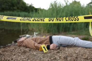 Adli tıp uzmanlığı. Cesedin bulunduğu olay yeri ve gölün yakınındaki işaret, seçici bir odak noktası.