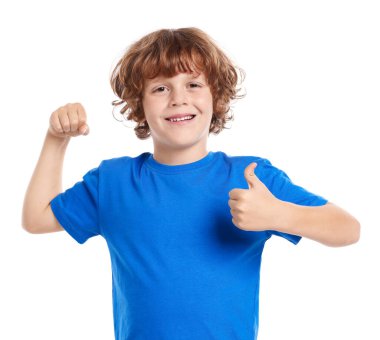 Kuvvet. Küçük mutlu çocuk beyaz arka planda bisepslerini ve başparmaklarını gösteriyor.