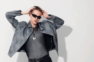 Beyaz arka planda ceket ve güneş gözlüğü takan yakışıklı genç adam, mesaj için yer var.