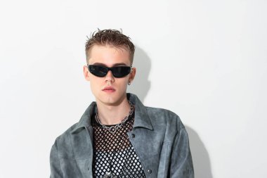 Beyaz arka planda ceket ve güneş gözlüğü takan yakışıklı genç adam, mesaj için yer var.