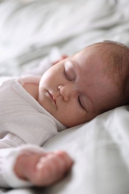 Sevimli yeni doğmuş bebek yatakta uyuyor, yakın plan.