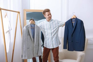 Hazırlanıyor. Genç adam evde kıyafet seçiyor.