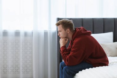 Evdeki yatakta oturan üzgün, düşünceli adam. Metin için boşluk