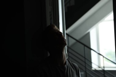 Üzüntü ve depresyon. Karanlık odada yorgun bir adam. Kapısı açık, penceresi açık.