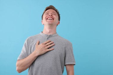 Açık mavi arka planda gülen yakışıklı bir adam. Pozitif duygu