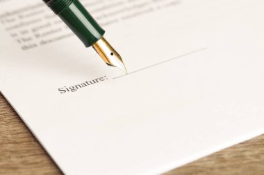 Tahta masadaki dolmakalemle noter belgesi imzalama, seçici odak