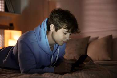 Ergen çocuk evde akıllı telefon kullanıyor.