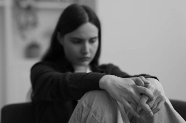 Evdeki kanepede oturan üzgün genç kadın. Siyah ve beyaz etkisi