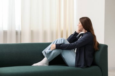 Evdeki kanepede oturan üzgün genç kadın, mesaj için yer var.