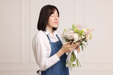 Beyaz duvarın yanında güzel çiçek buketi olan bir çiçekçi.