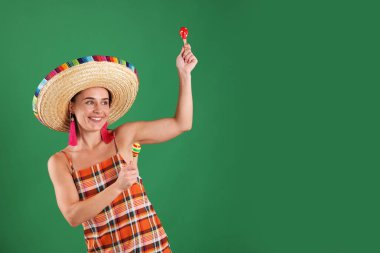 Yeşil arka planda marakas çalan şapkalı gülümseyen kadın. Metin için boşluk