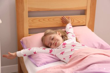 Küçük kız evde yatakta uyanıyor.