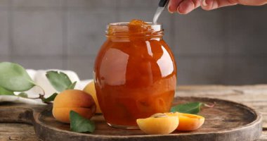 Lezzetli kayısı reçeli ve ahşap masada taze meyveli kadın, yakın plan.