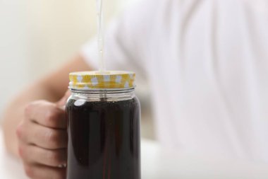 Bulanık arka planda serinletici gazoz kavanozu olan adam, yakın plan.