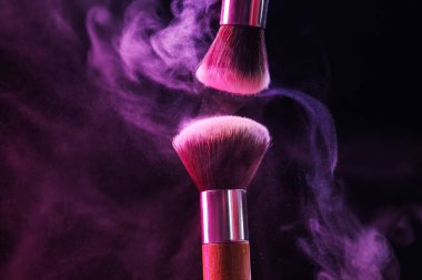 Renkli göz gölgeli makyaj fırçaları siyah arka planda neon ışıkları, yakın plan