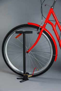 Gri arkaplanda bisiklet ve manuel hava pompası, yakın plan.