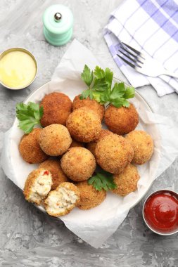 Gri desenli masada servis edilen maydanozlu ve soslu leziz kızarmış köfteler.
