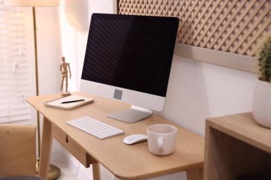 Ev ofisinde ahşap masası, bilgisayarı ve kırtasiyesi olan şık bir iş yeri, yakın çekim. İç tasarım