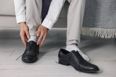 Hazırlanıyor. Genç adam evde şık ayakkabılar giyiyor, yakın plan.