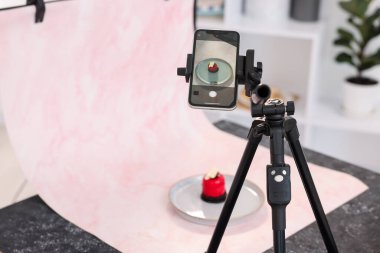 Stüdyoda akıllı telefonla lezzetli bir tatlı çekmek, seçici bir odak noktası. Profesyonel yemek fotoğrafçılığı.