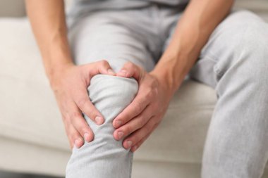 Kanepede diz ağrısı çeken bir adam, yakın plan.