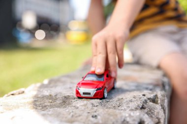 Küçük çocuk dışarıda oyuncak arabayla oynuyor, yakın plan.