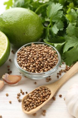 Kişniş çekirdeği, taze kişniş, kireç ve sarımsak açık ahşap masa, yakın plan.