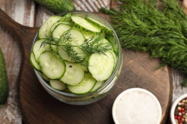 Turşu yapıyorum. Açık kavanozda taze salatalıklar, ahşap masada baharatlar ve dereotlar.