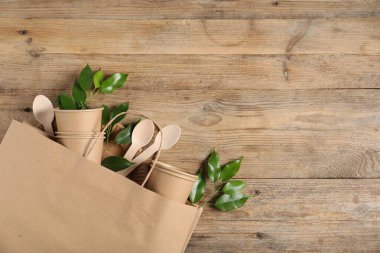 Farklı çevre dostu ambalajlar ve ahşap arka planda yapraklar, üst manzara. Metin için boşluk