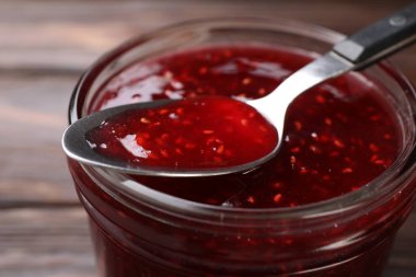 Cam kavanozda tatlı ahududu reçeli ve masada kaşık, yakın plan.