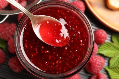 Cam kavanozdan kaşıkla ahududu reçeli alıp masanın üstüne koyuyoruz.