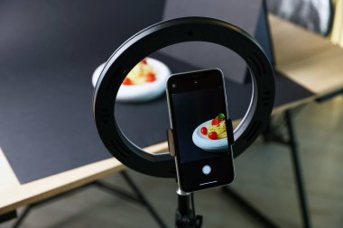 Stüdyoda akıllı telefonla lezzetli makarna çekmek, ekrana odaklanmak. Profesyonel yemek fotoğrafçılığı.