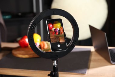 Stüdyoda akıllı telefonla sebze çekmek, ekrana odaklanmak. Profesyonel yemek fotoğrafçılığı.