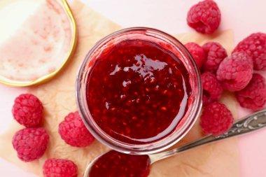 Cam kavanozda tatlı ahududu reçeli ve pembe ahşap masada böğürtlen.