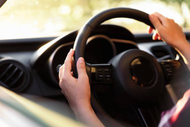 Güneşli bir günde modern arabanın direksiyonundaki kadın, yakın plan.