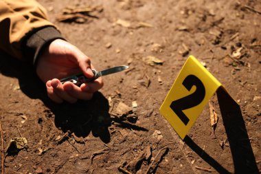 Adli tıp uzmanlığı. Cesedin olduğu olay yeri, bıçak ve işaret açık havada, yakın plan.