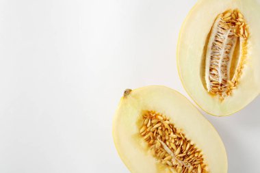 Beyaz arka planda olgun kavun yarımları, düz uzanmış. Metin için boşluk