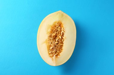 Açık mavi arkaplanda olgun kavunun yarısı, üst görünüm