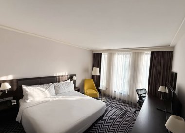 Büyük rahat bir yatak, şık bir otel odasında koltuk ve lambalar.