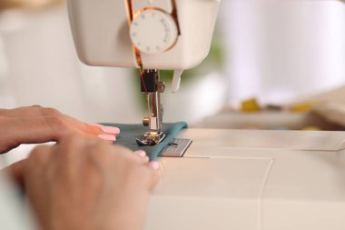 Atölyede dikiş makinesi ve kumaşla çalışan bir kadın.