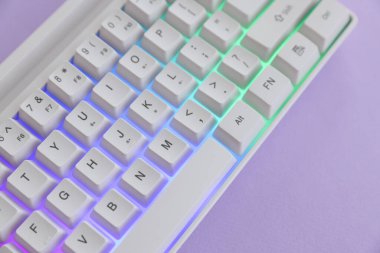 Menekşe arkaplan üzerinde RGB ışıklandırması olan modern bilgisayar klavyesi, yukarıda görünüm