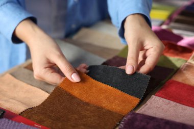 Kadın farklı örnekler arasından kumaşı seçiyor, kapalı alanda, yakın plan.