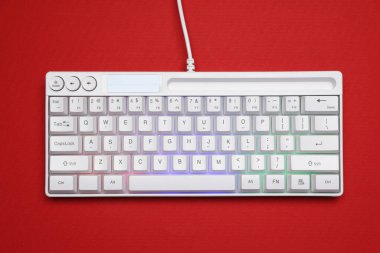 Kırmızı arkaplanda RGB ışıklandırması olan modern beyaz klavye, üst görünüm