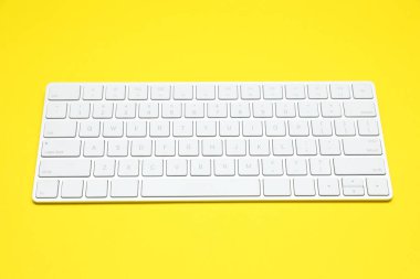 Sarı arkaplanda modern beyaz kablosuz klavye