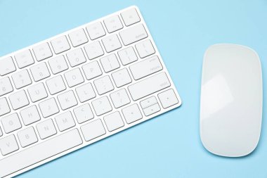 Açık mavi zemin üzerinde modern beyaz kablosuz klavye ve fare, üst görünüm